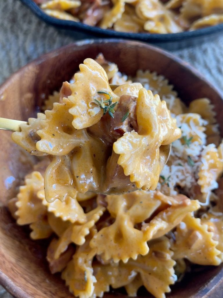 Creamy chorizo and bacon pasta scooped in a spoon, showing the rich sauce coating the farfalle