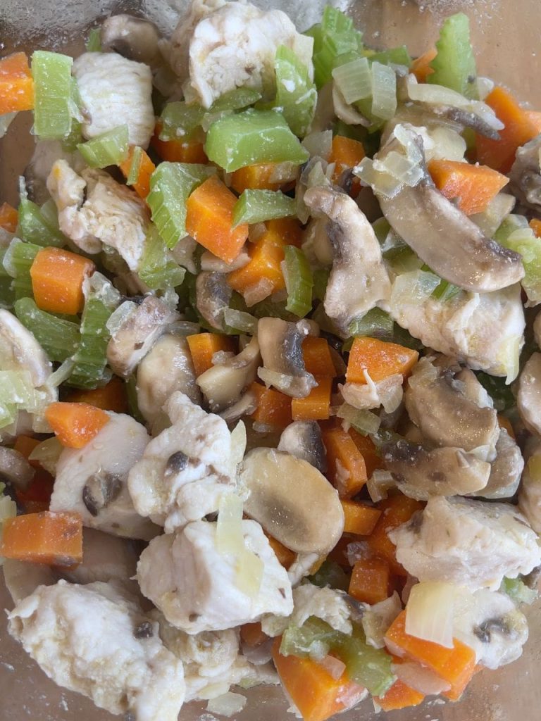 Diced chicken mixed with vegetables and sliced mushrooms in a bowl