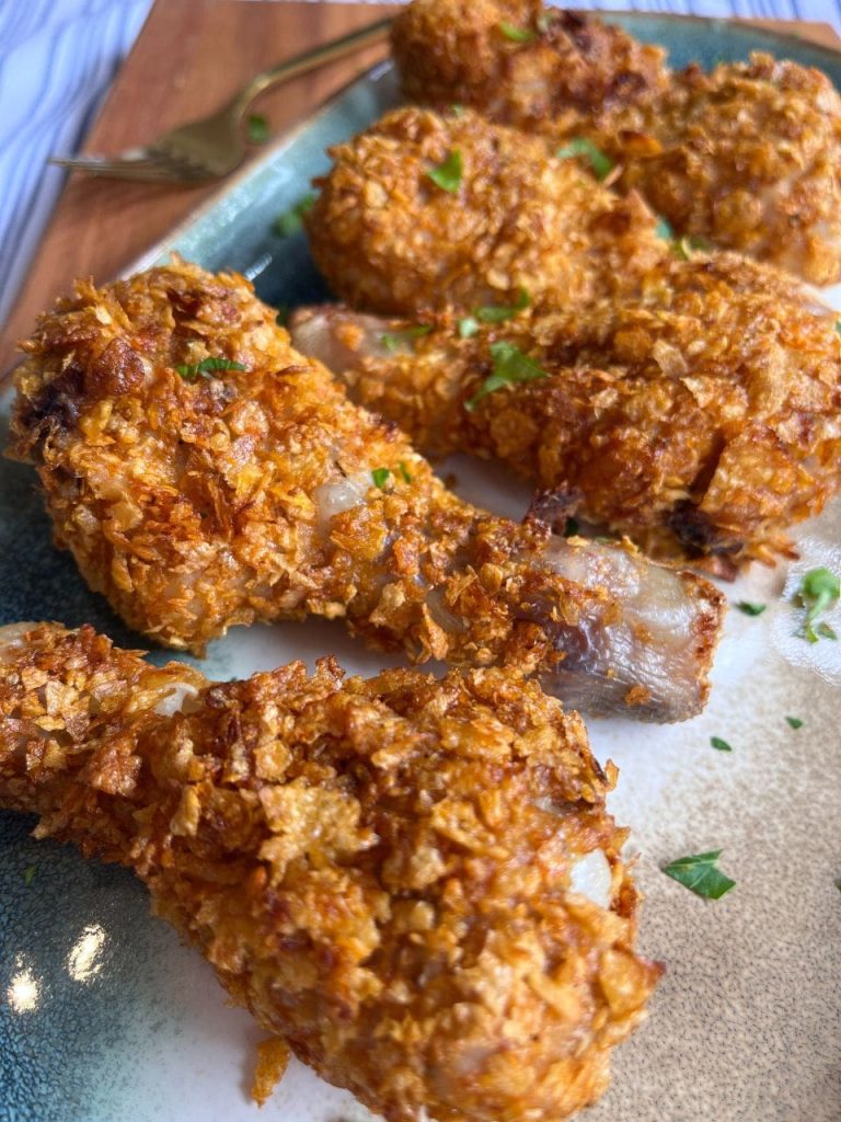 Golden crispy chicken drumsticks served on a platter, garnished with fresh parsley