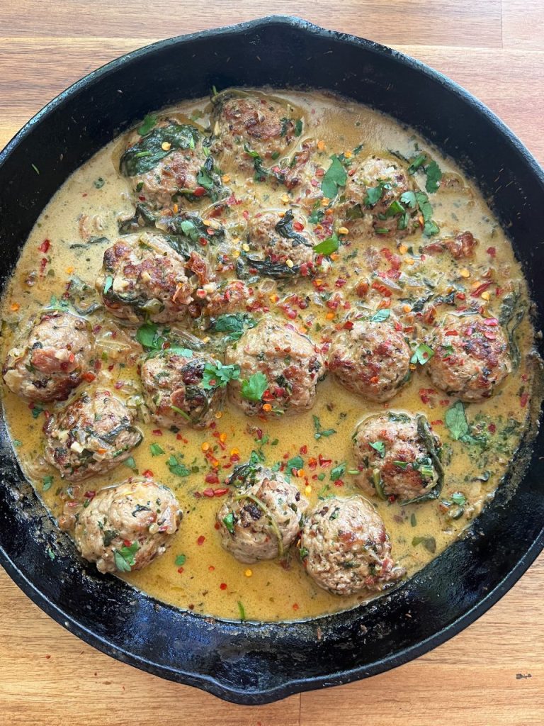 Pork meatballs coated in creamy sun-dried tomato sauce, garnished with fresh parsley