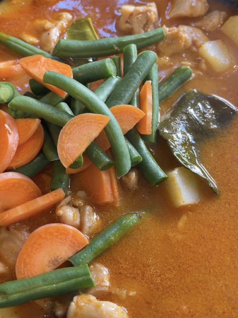 Carrots and green beans simmering in the rich red curry sauce, absorbing flavours