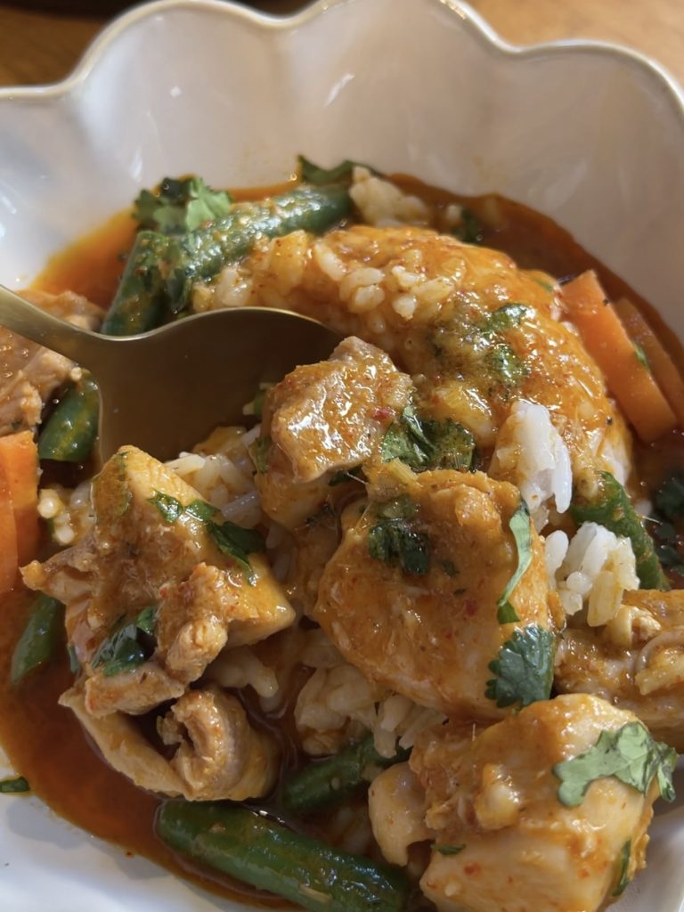 Close-up of red curry with chicken, potatoes, and vegetables, showing the rich sauce coating each ingredient
