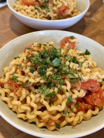 Cherry tomato and lemon pasta served on a white bowl, garnished with fresh parsley