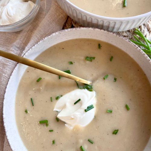Close-up of velvety soup with a swirl of crème fraîche and finely chopped chives on top