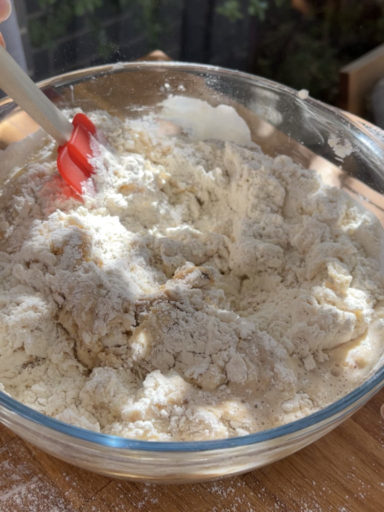 Bread flour, spices, sugar, salt, butter, egg, and chocolate chips added to the bowl, forming a shaggy dough