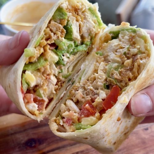 Close-up of chopped chicken crunch wrap halves with spicy mayo in a white bowl