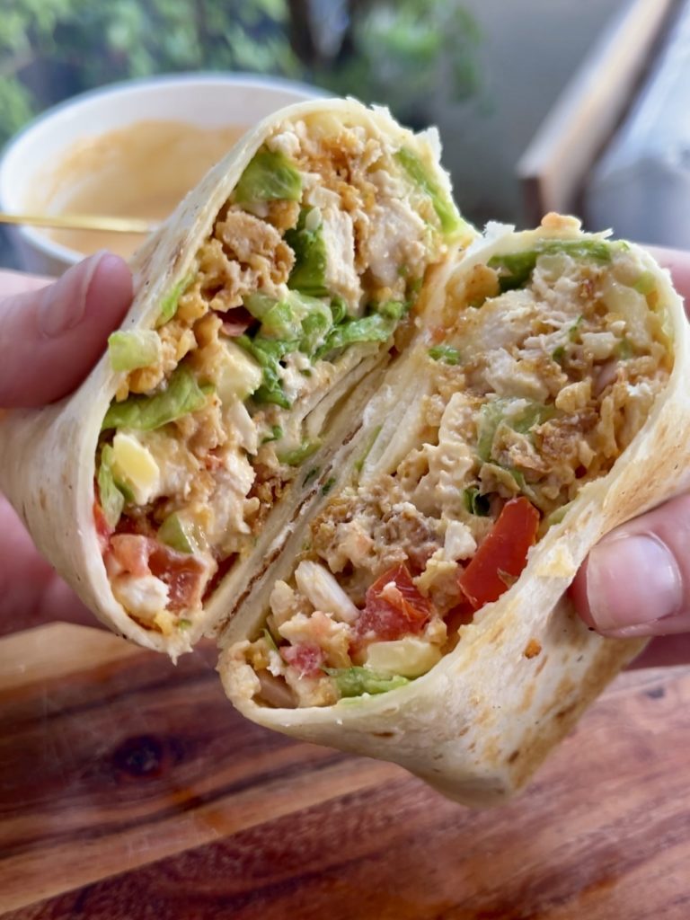 Close-up of chopped chicken crunch wrap halves with spicy mayo in a white bowl