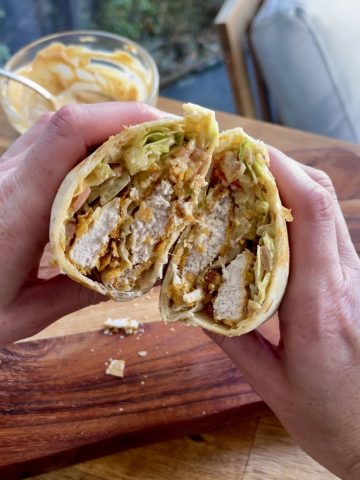 Crispy chicken cornflake wrap cut in half, filled with golden chicken, fresh lettuce, tomato, cheese, and bacon
