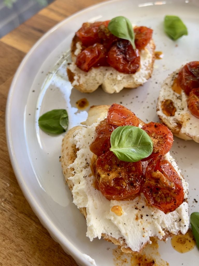 Close-up of creamy whipped feta spread and juicy roasted tomatoes on golden baguette slices