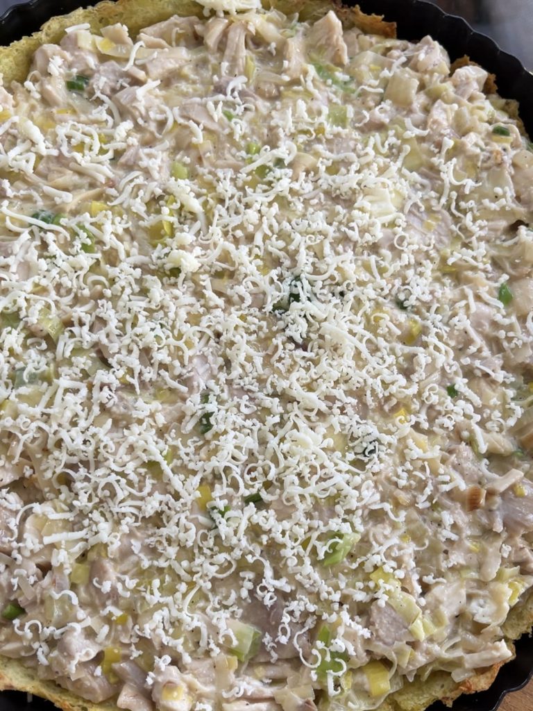 Creamy chicken and leek tart waiting to be baked until golden, topped with fresh mozzarella