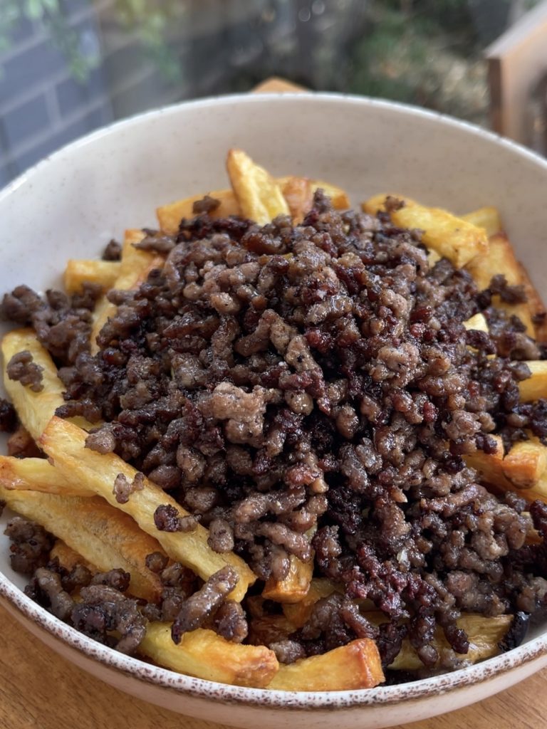 Crispy baked fries layered in a wide bowl with cooked beef mince spread evenly on top