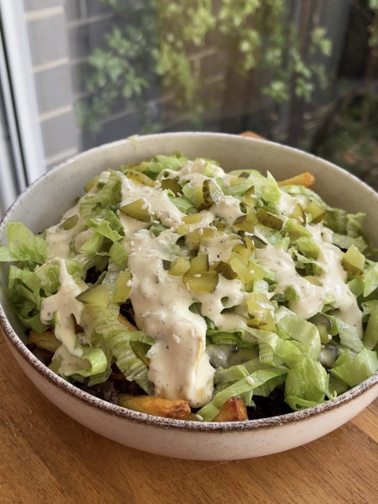 Loaded fries topped with lettuce, burger sauce, extra pickles, and a sprinkle of sesame seeds