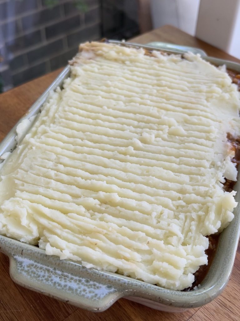 Mashed potatoes whipped with milk and butter, spread evenly over the shepherd’s pie filling with forked texture on top
