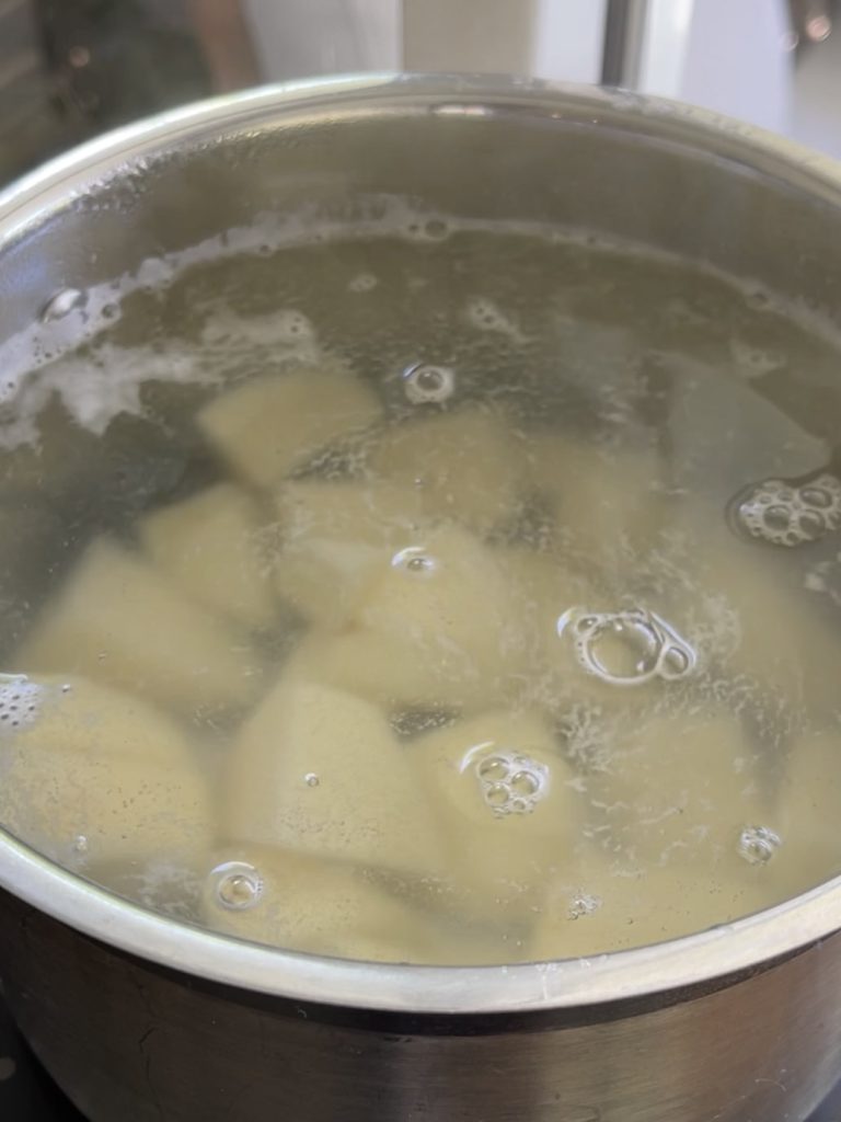 Potatoes boiling in a saucepan of water until soft, ready for mashing