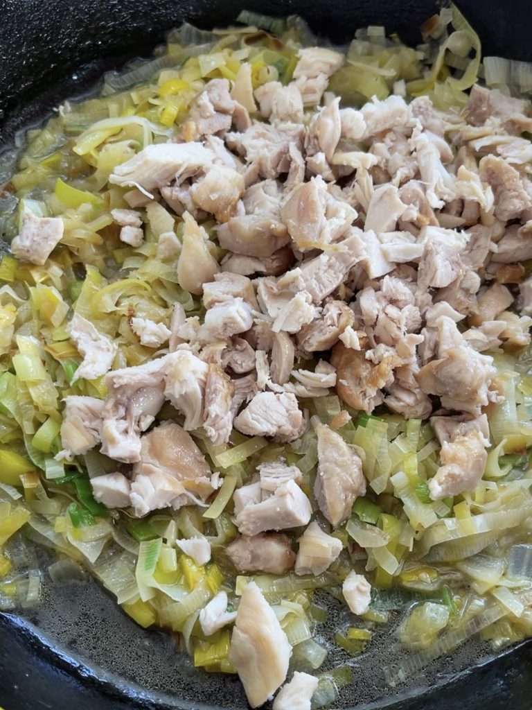 Shredded chicken and chicken stock waiting to be stirred into the pan with the leeks, just warmed through