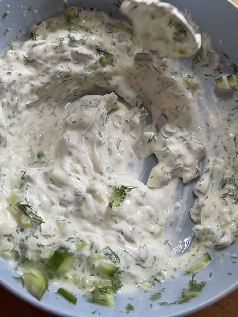 Tzatziki ingredients—Greek yoghurt, garlic, cucumber, dill, lemon juice, salt and pepper—mixed in a bowl