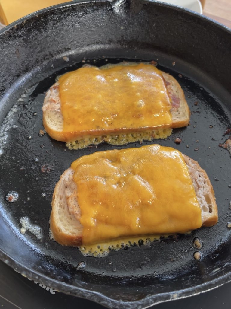 Close-up of cheese melting on a sausage and egg sandwich, preparing for assembly