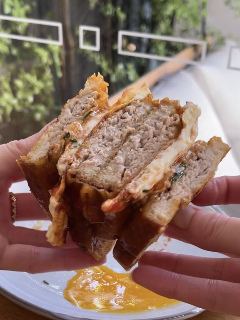 Delicious sausage and egg sandwich being held, perfect for a quick breakfast or brunch