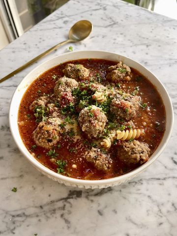 Easy Meatball Soup in a bowl with small elbow pasta, fresh basil, and tender meatballs