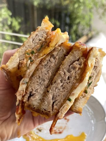 Homemade sausage and egg breakfast sandwich with golden-brown bread, fried egg, and melted cheese.