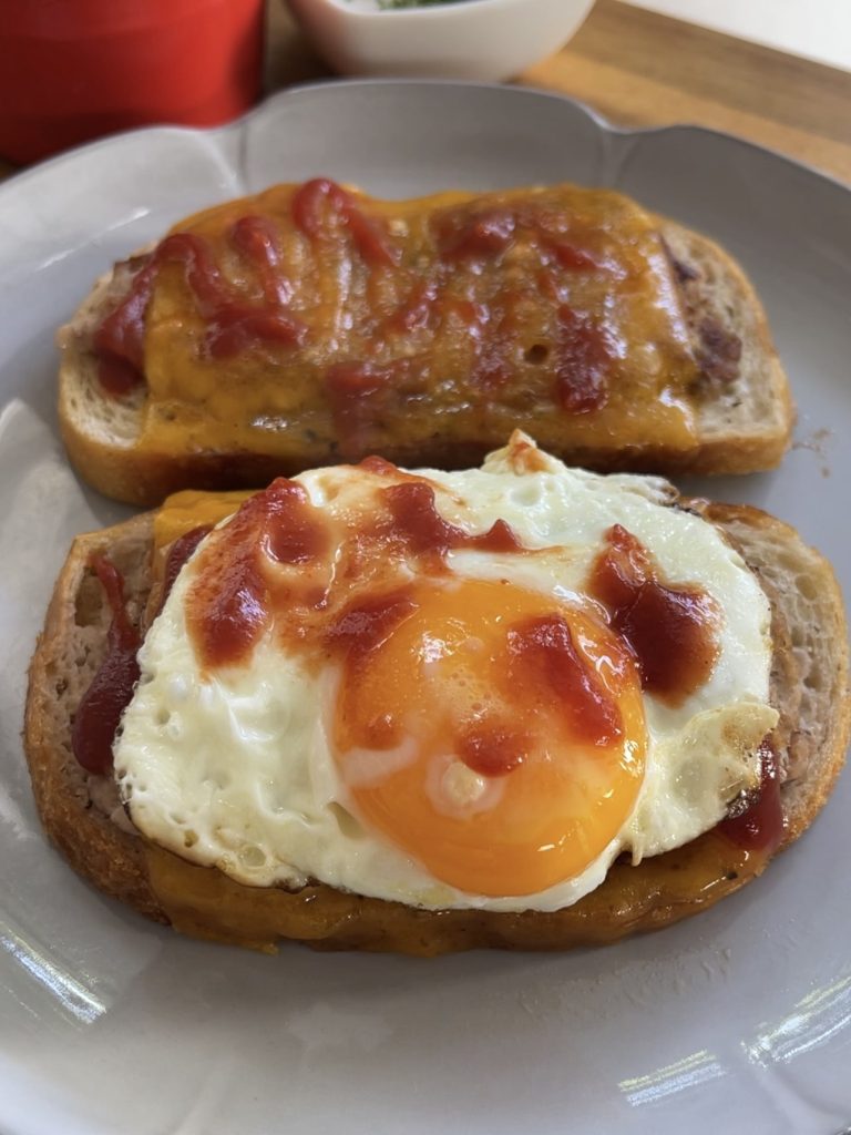 Sunny side egg on sausage and egg sandwich with tomato sauce