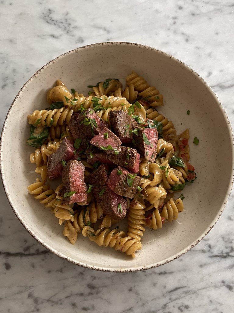 One pan cajun pasta and steak served hot, creamy sauce coating each piece perfectly
